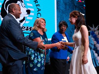 student shaking admins hands on stage